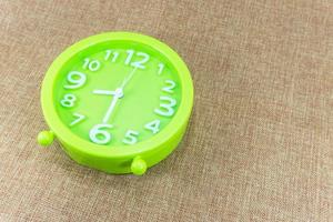 Green alarm clock on brown sackcloth background show half eight o'clock or 8.30 a.m. photo