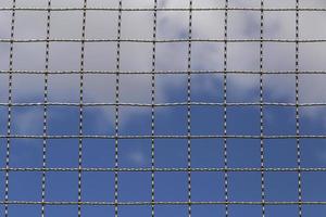 metal net against blue sky with clouds photo