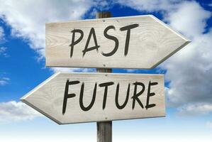 Future, Past - Wooden Signpost with Two Arrows and Cloudy Sky in Background photo