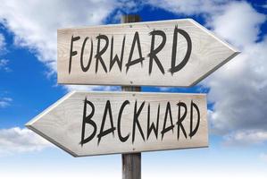 Forward, Backward - Wooden Signpost with Two Arrows and Cloudy Sky in Background photo