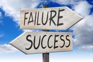 Success, Failure - Wooden Signpost with Two Arrows and Cloudy Sky in Background photo