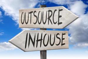 Outsource, Inhouse - Wooden Signpost with Two Arrows and Cloudy Sky in Background photo
