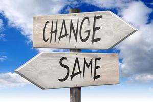 Same, Change - Wooden Signpost with Two Arrows and Cloudy Sky in Background photo