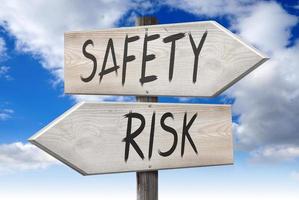 Risk, Safety - Wooden Signpost with Two Arrows and Cloudy Sky in Background photo