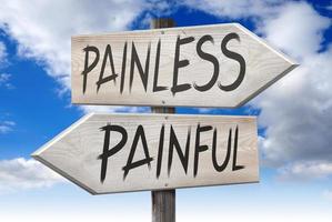 Painfull, Painless - Wooden Signpost with Two Arrows and Cloudy Sky in Background photo