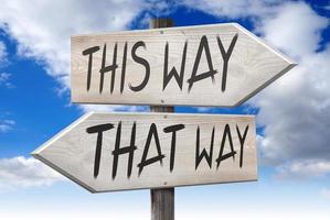 This Way, That Way - Wooden Signpost with Two Arrows and Cloudy Sky in Background photo