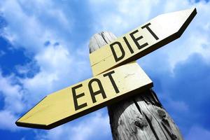 Eat, Diet - Wooden Signpost with Two Arrows and Sky in Background photo