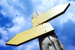 Empty Wooden Signpost with Two Arrows and Cloudy Sky in Background photo