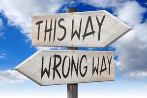 This Way, Wrong Way - Wooden Signpost with Two Arrows and Cloudy Sky in Background photo