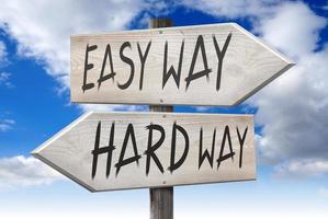 Easy Way, Hard Way - Wooden Signpost with Two Arrows and Cloudy Sky in Background photo