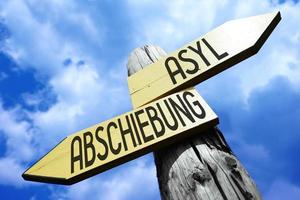 Asylum, Rejection in German - Wooden Signpost with Two Arrows and Sky in Background photo