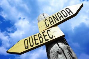 Canada, Quebec - Wooden Signpost with Two Arrows and Sky in Background photo