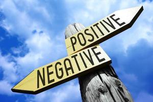 Positive, Negative - Wooden Signpost with Two Arrows and Sky in Background photo