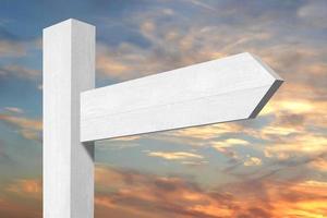 White Wooden Signpost with one Arrow and Sunset Sky in Background photo