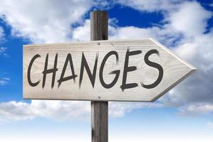 Changes Ahead - Wooden Signpost with one Arrow and Cloudy Sky in Background photo