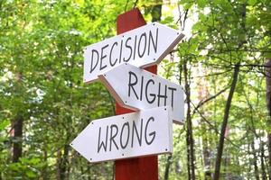 Decision, Right, Wrong - Wooden Signpost with Three Arrows, Forest in Background photo