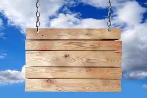 de madera tablero colgando en cadenas con nublado cielo en antecedentes foto
