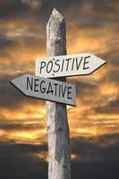 Positive or Negative - Wooden Signpost with Two Arrows and Sunset Sky photo