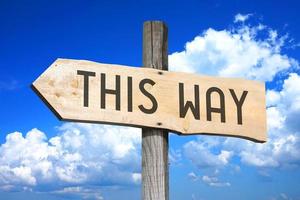 This Way - Wooden Signpost with one Arrow, Sky with Clouds in Background photo