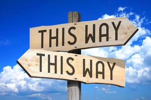 This Way, This Way - Wooden Signpost with Two Arrows, Sky with Clouds in Background photo