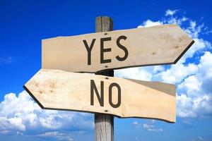 Yes, No - Wooden Signpost with Two Arrows, Sky with Clouds in Background photo