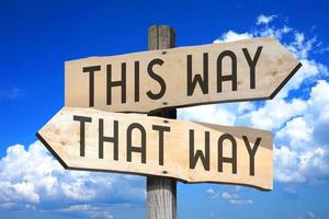 This Way, That Way - Wooden Signpost with Two Arrows, Sky with Clouds in Background photo