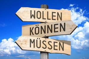 Want, Can, Must in German - Wooden Signpost with Three Arrows photo