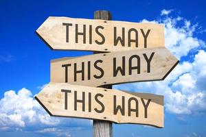 This Way Concept - Wooden Signpost with Three Arrows, Sky with Clouds in Background photo