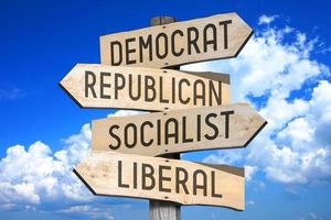 Democrat, Republican, Socialist, Liberal - Wooden Signpost with Four Arrows, Sky with Clouds in Background photo