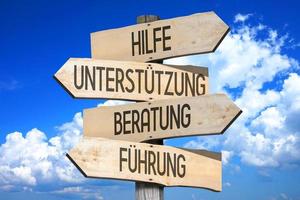 Help, Support, Advice, Guidance in German - Wooden Signpost with Four Arrows photo