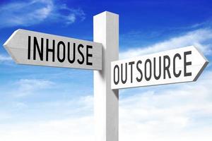 Outsource, Inhouse - Wooden Signpost with Two Arrows and Sky in Background photo