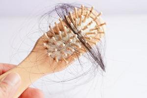 Asian woman have problem with long hair loss attach to comb brush. photo