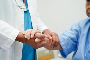 médico tomados de la mano paciente anciana asiática, ayuda y atención en el hospital. foto