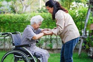 Doctor help Asian elderly woman disability patient sitting on wheelchair in park, medical concept. photo