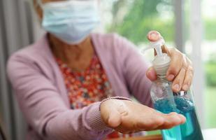 Asian senior woman press blue alcohol sanitizer gel for washing hand protect infection coronavirus.