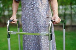 Asian elderly woman disability patient walk with walker in park, medical concept. photo