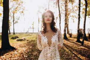 A portrait of a dreamy lady in a wedding dress posing indoor with flowers. Wedding, beauty, fashion. photo