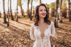 belleza retrato de un hermosa rubia novia en velo con un ramo de flores de flores en su manos en un gris antecedentes. foto