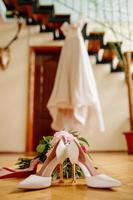 female feet in white wedding sandals with a bouquet of camomiles photo