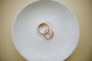 Golden wedding rings on white plate photo