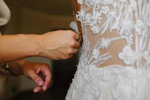 Wedding preparation, wedding gown being tied up photo