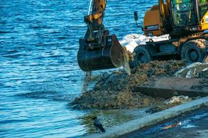 Dnepropetrovsk, Ukraine - 11.26.2021 Excavator works to strengthen the embankment. Hydraulic excavator working on the river bank. photo