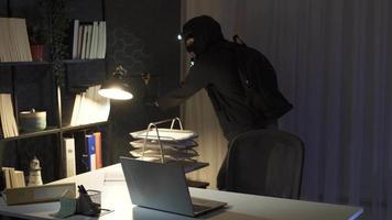 ladrón hombre comete robo con Linterna en oficina. el ladrón entrando el oficina es mirando para valores a robar con un Linterna. video