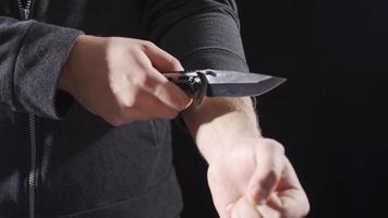 a cometer suicidio, a cortar con un cuchillo. agresivo punk hombre participación cuchillo y haciendo peligroso se mueve video