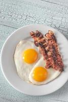 Fried eggs and bacon on the white plate photo