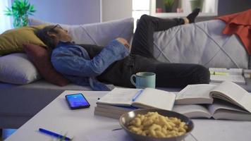 fatigué paresseux homme mensonge sur le canapé étant réveillé en haut par le alarme horloge. il atteint pour le sien cellule téléphone sur le table et roupille le alarme l'horloge sur le sien téléphone intelligent écran dans le de bonne heure Matin. video