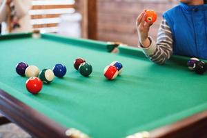 balls on a billiard table in a triangle. child playing billiards photo