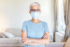 Senior woman in respiratory mask. Masked woman looks at camera. Cold, flu, virus, tonsillitis, respiratory disease, quarantine, epidemic concept. photo