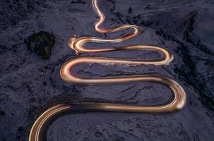 un serpiente conformado pasar la carretera fotografiado a Luz de noche pintura foto