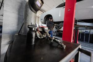 Set of tools on the shelf against mechanic in service repair station working with muscle car. photo